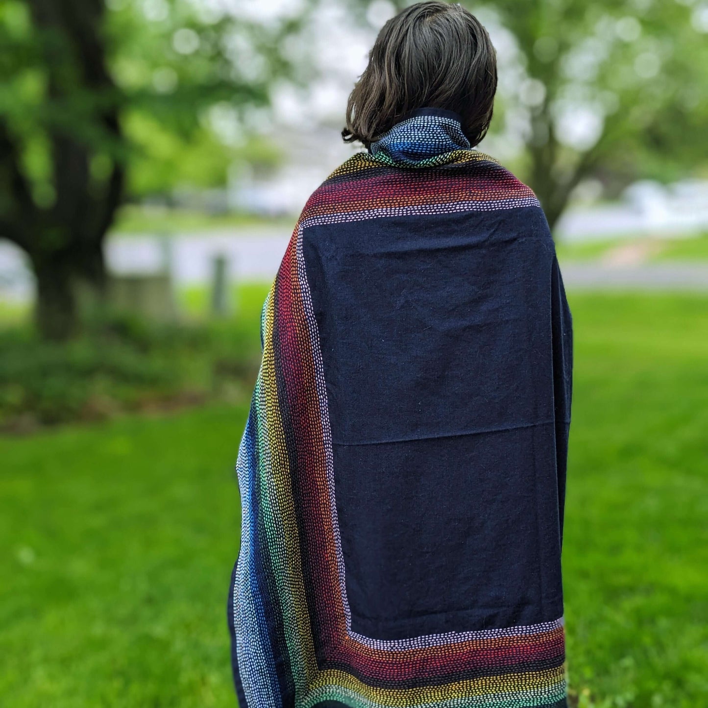 Person draped in Shiawase Sashiko Furoshiki with 15 colorful sashiko threads, showcasing Japanese stitching on fabric outdoors.