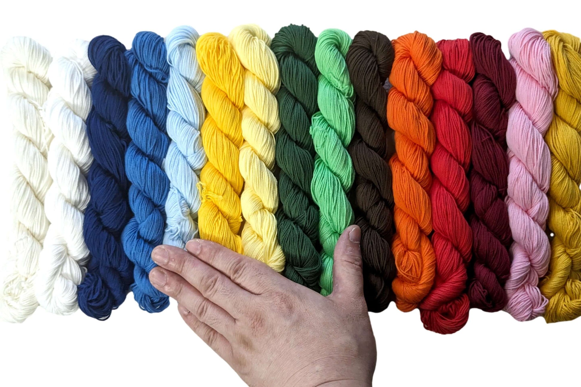A hand touching an array of colorful Sashiko threads in various mono colors, showcasing traditional Japanese stitching materials.