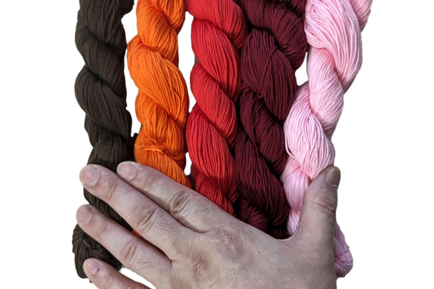 Hand holding skeins of traditional Sashiko thread in mono colors, made from 100% Egyptian cotton, manufactured in Japan.
