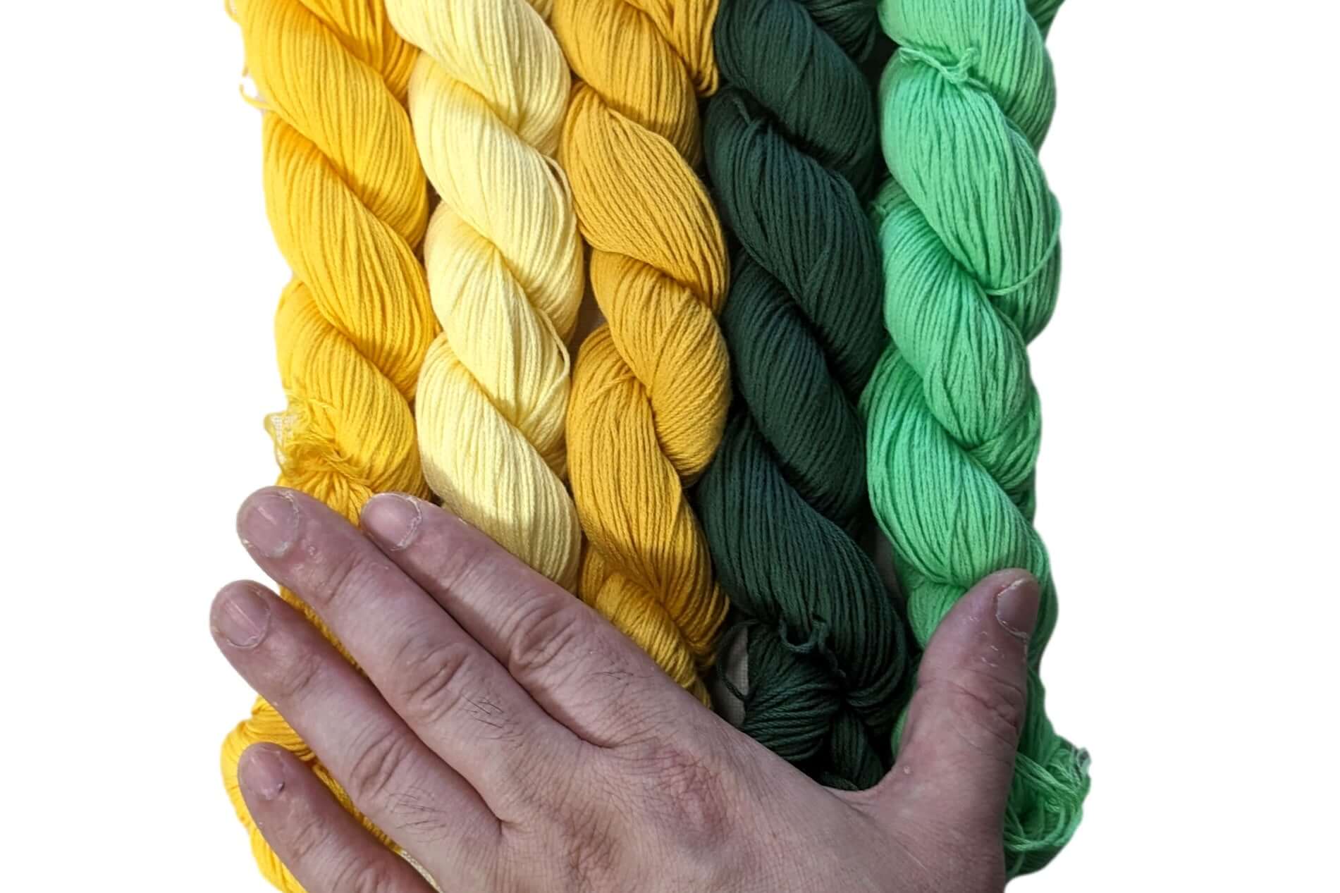 Hand holding skeins of traditional Sashiko thread in yellow and green colors for Japanese embroidery